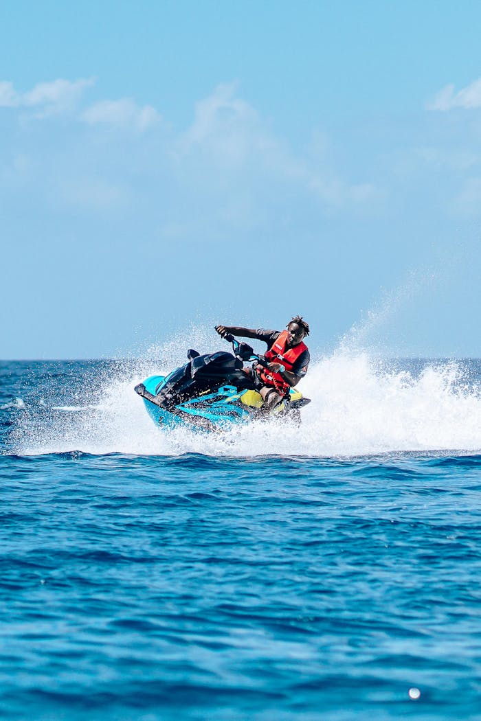 Man enjoying an exhilarating jet ski ride on the open sea under a clear blue sky.